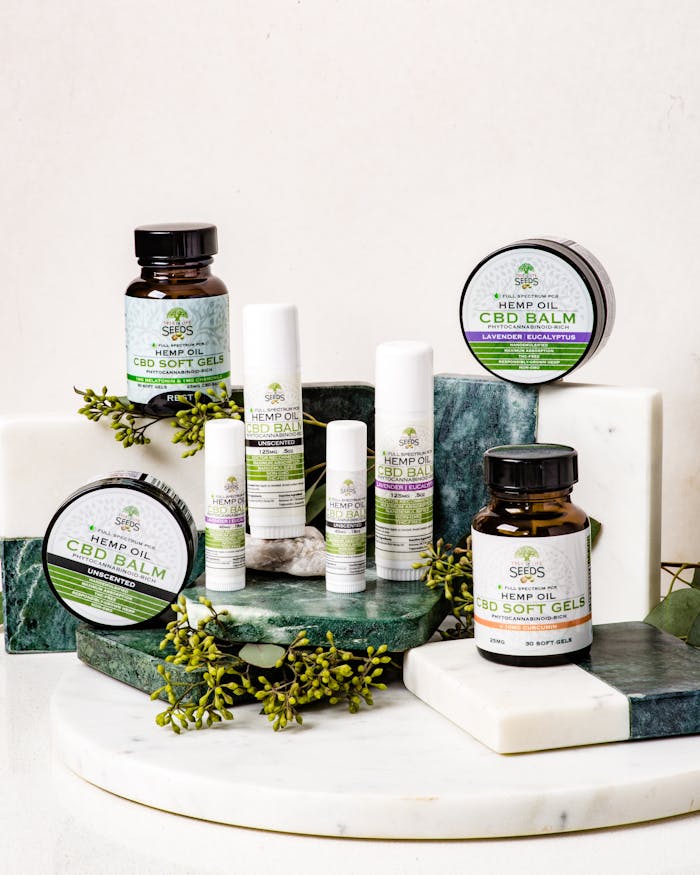 An assortment of CBD products including balms and softgels arranged on a marble stand.
